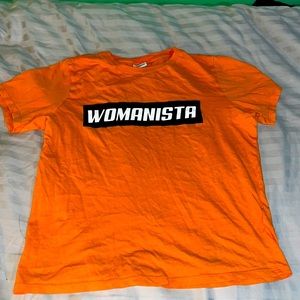 Orange tee, text: “Womanista”